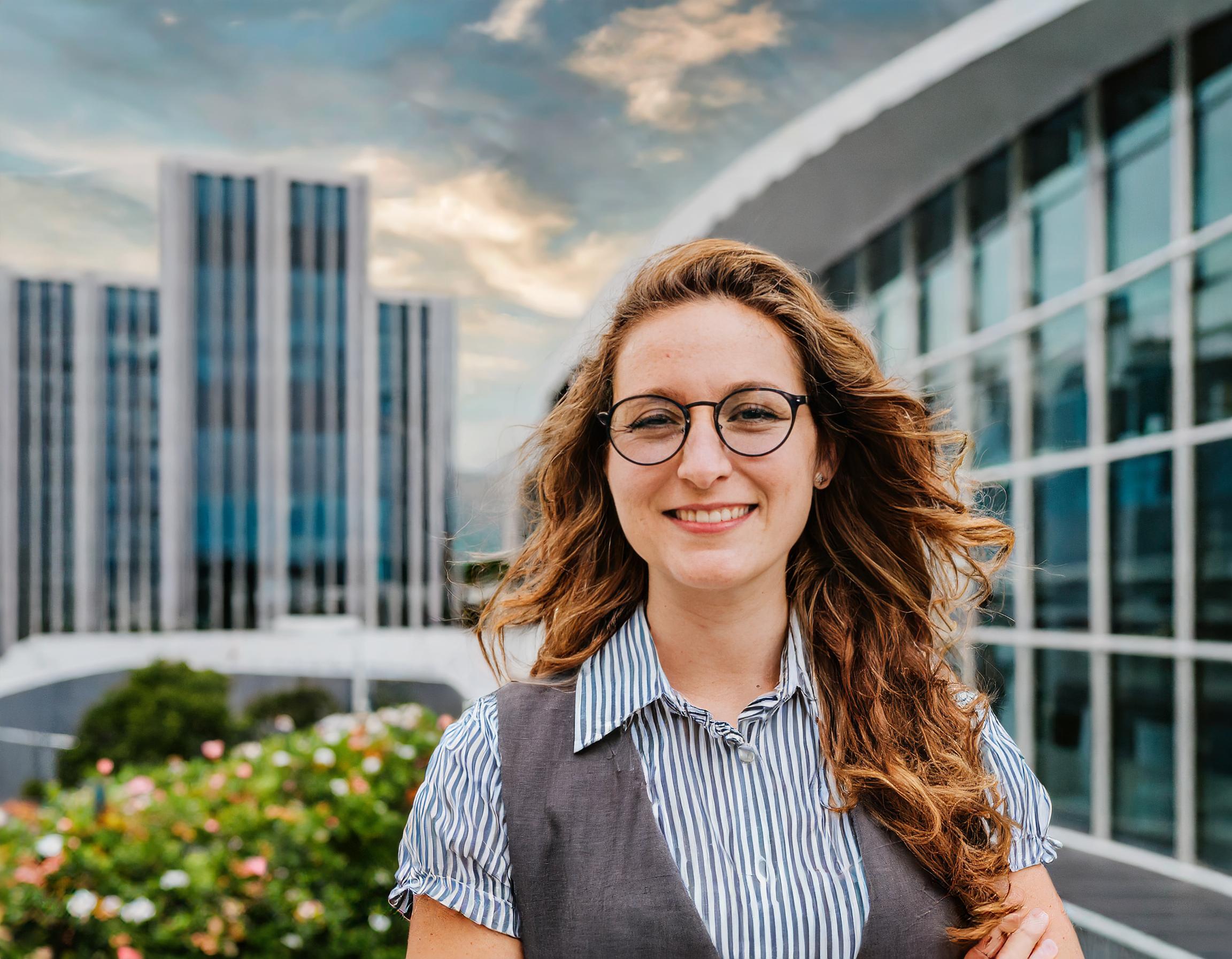 Junge Frau mit blonden Haaren, in einem klassischen Business-Outfit, lächelnd